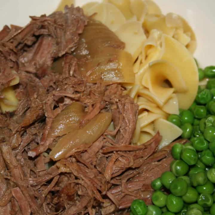 slow cooker roast beef recipe served with green peas and egg noodles