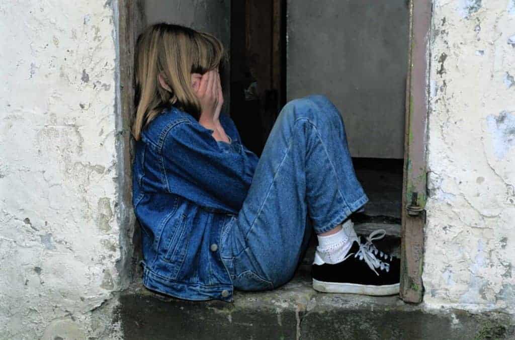girl sitting on a stoop covering her face