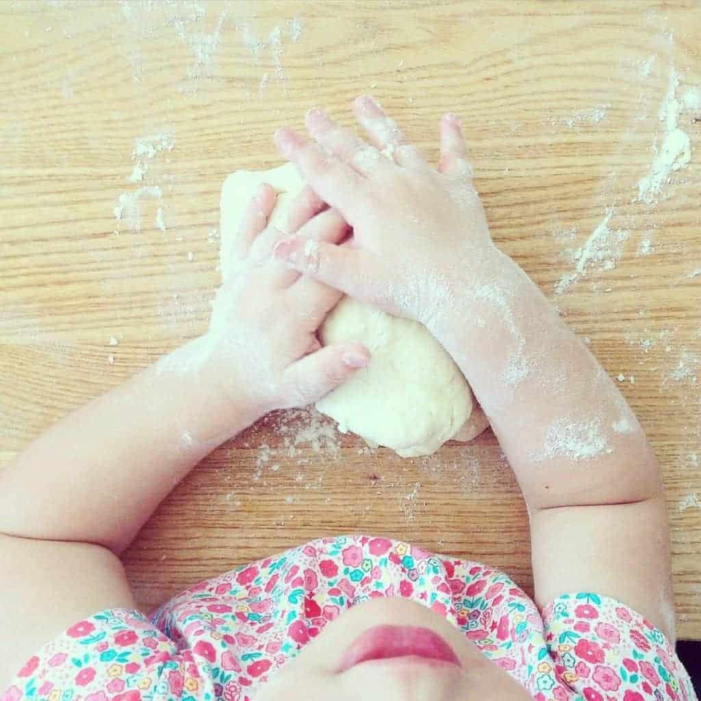 Toddler working with dough as she learns about cooking.